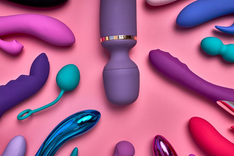 various sex toys sprawled over a pink backdrop